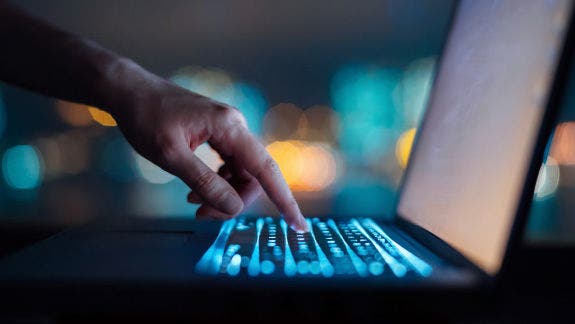 Hand and laptop with backlit keyboard