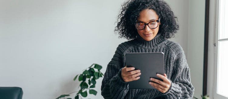 Young woman wearing glasses watching something on her digital tablet (copy space).