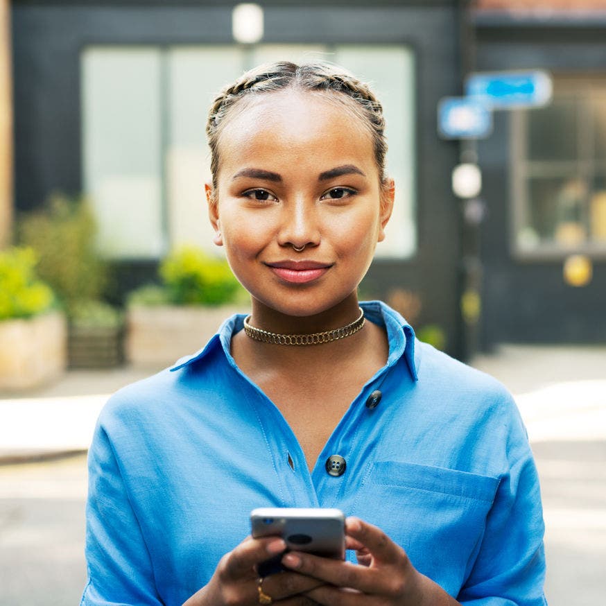 woman looking serenely at the viewer while holding a smartphone