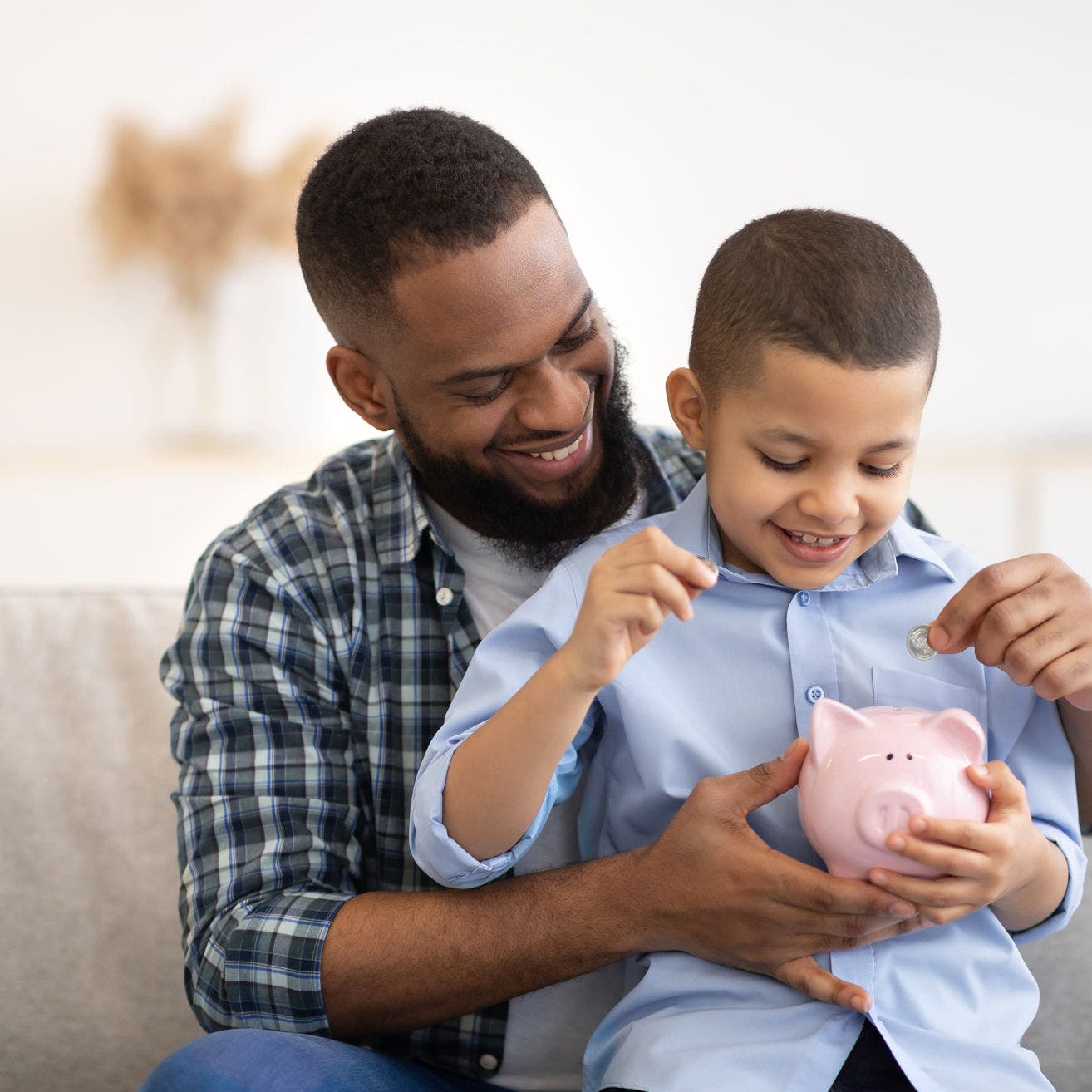 Father and son adding change to piggy bank