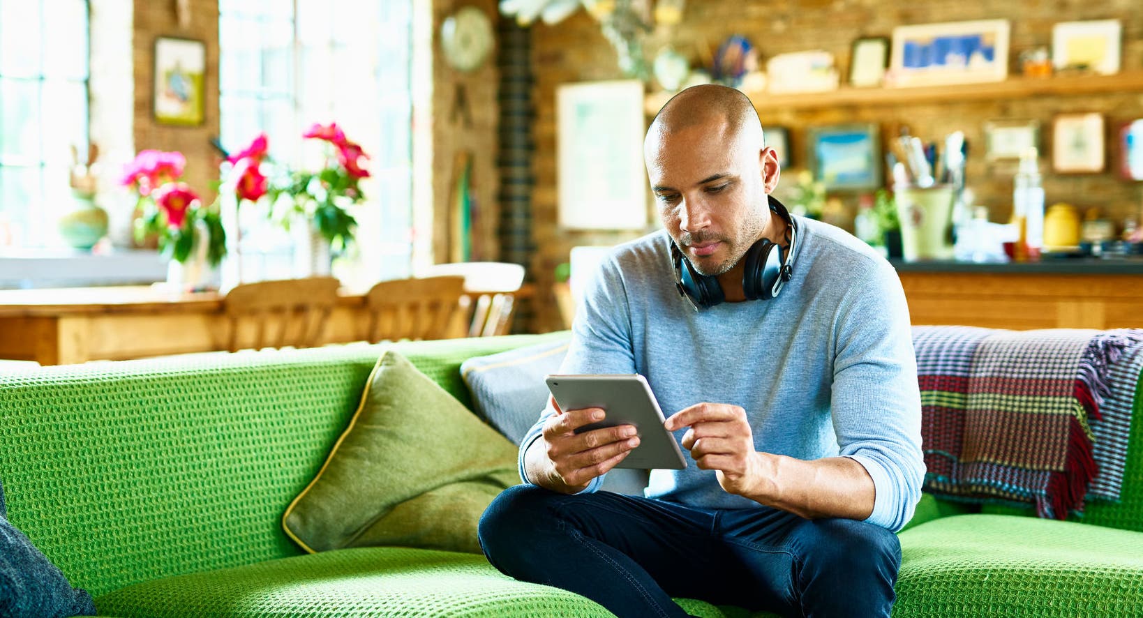 Man sitting on green sofa and using tablet