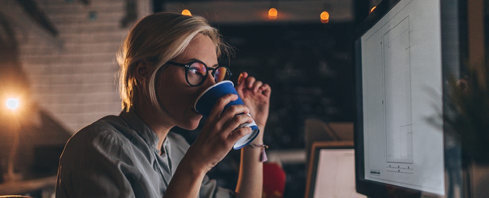 woman sipping coffee looking at computer
