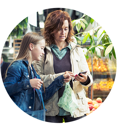 Woman and daughter standing in a grocery store aisle looking at phone