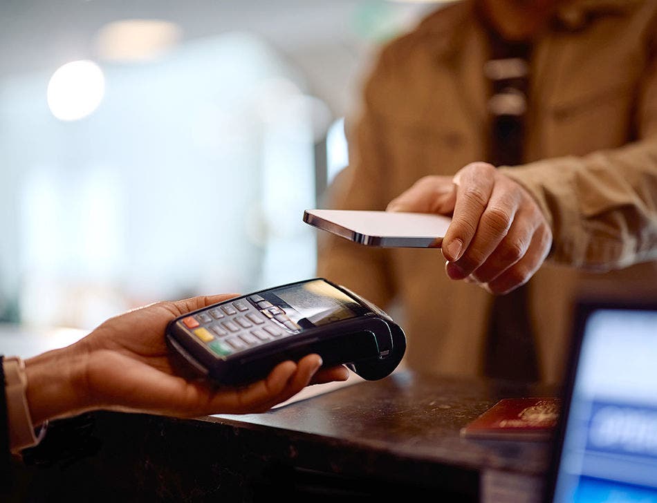 pos hand with phone holding over hand held check out device
