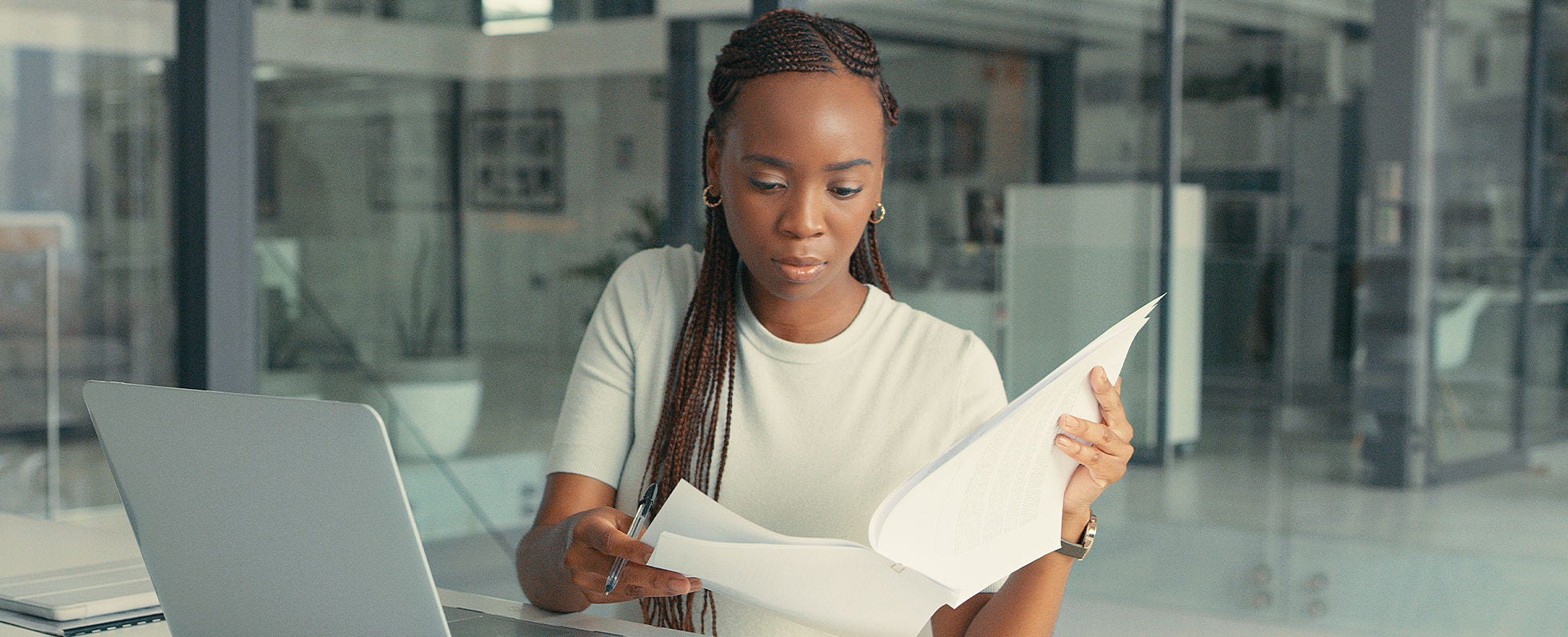 Woman in front of computer looking at documents. 