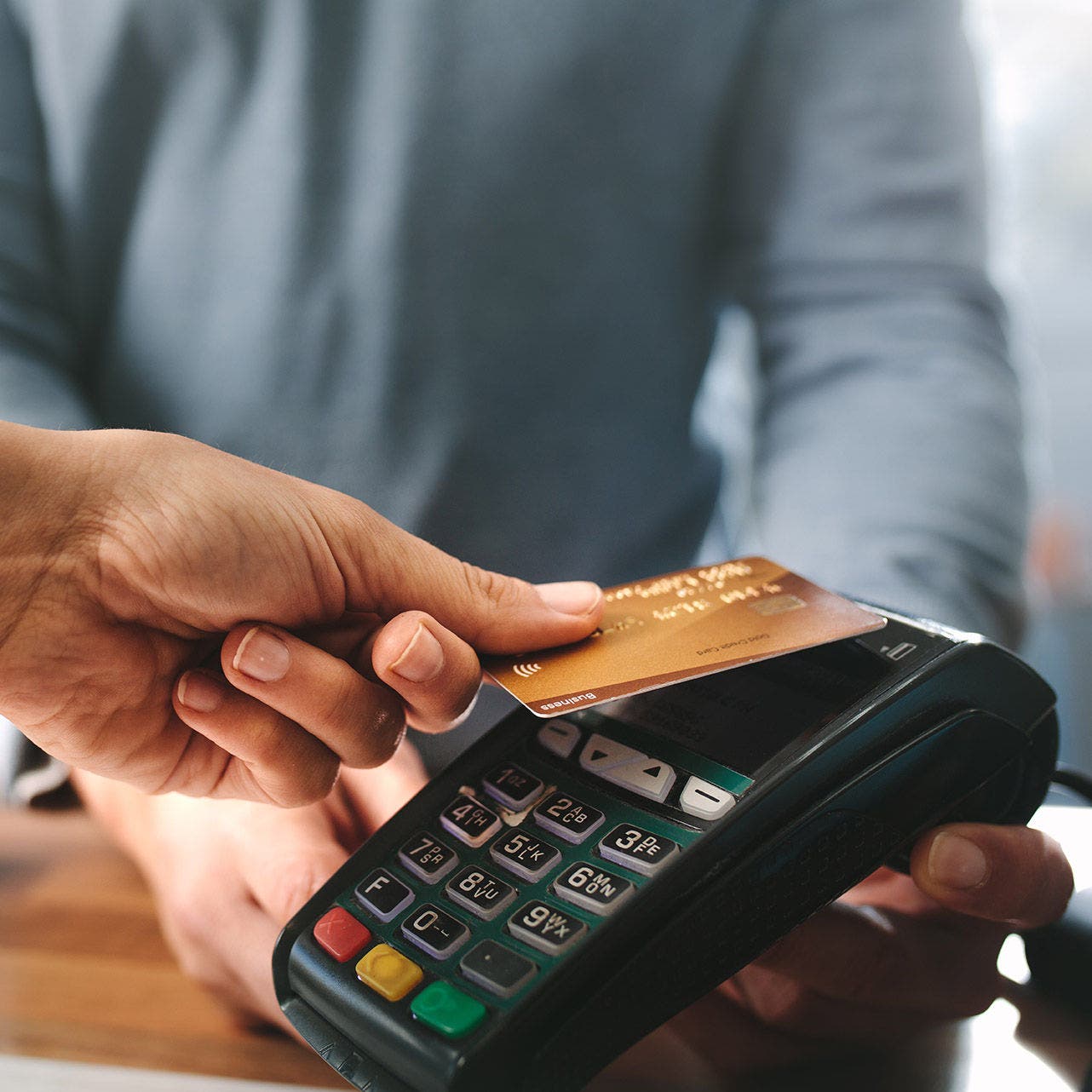 Pharmacist accepting credit card by contactless payment.  Woman purchasing products in the pharmacy. Pharmacist hands charging with credit card reader.