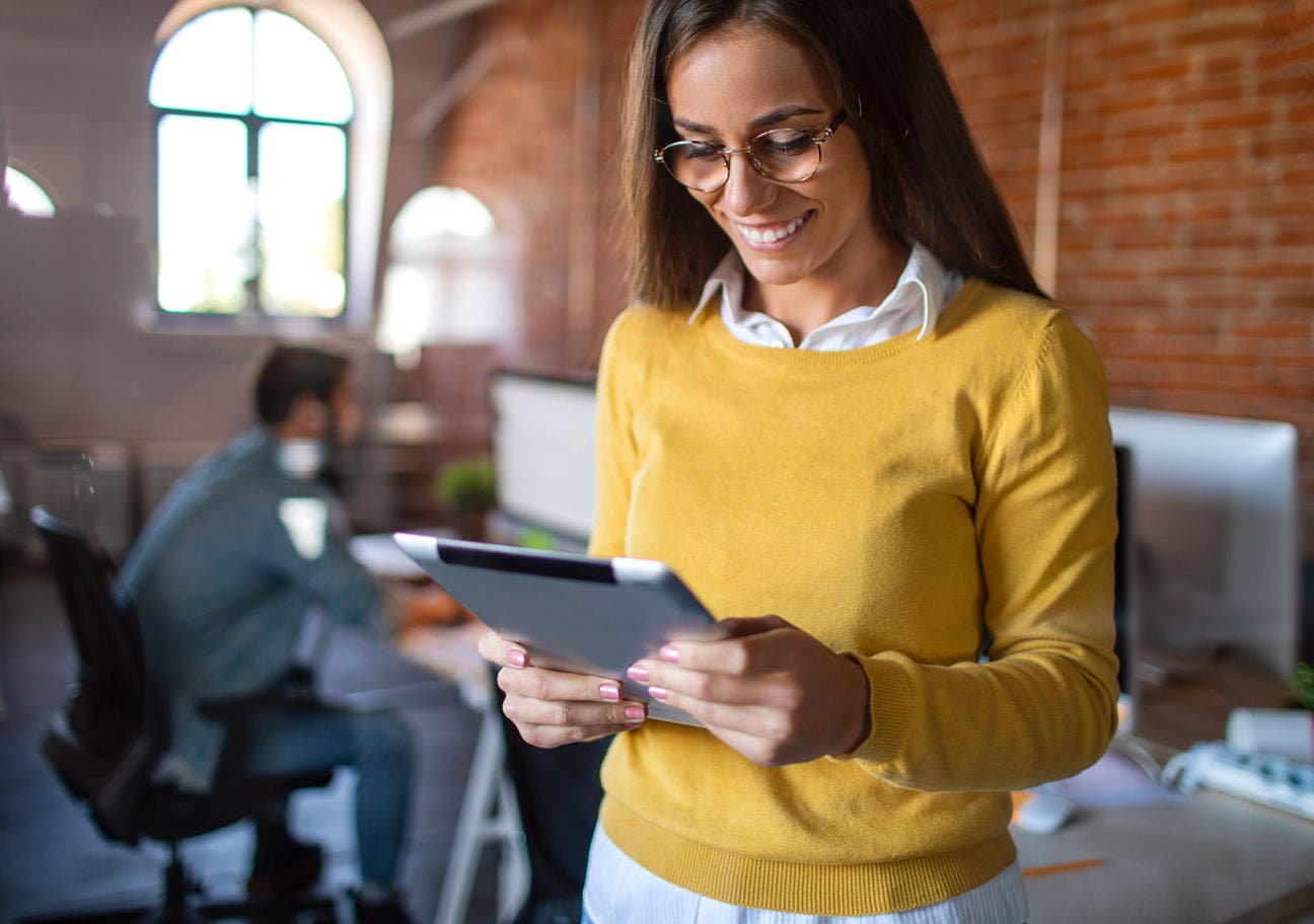 woman standing in a casual office looking at a tablet