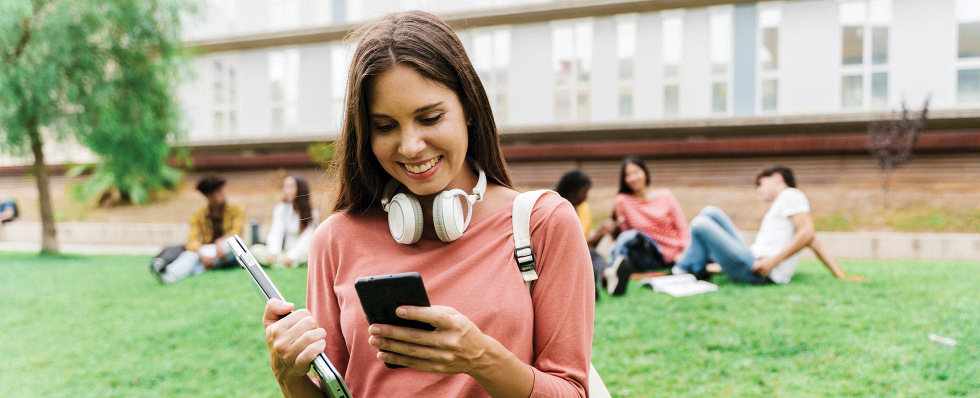  Young woman on a college campus looking at her phone. 