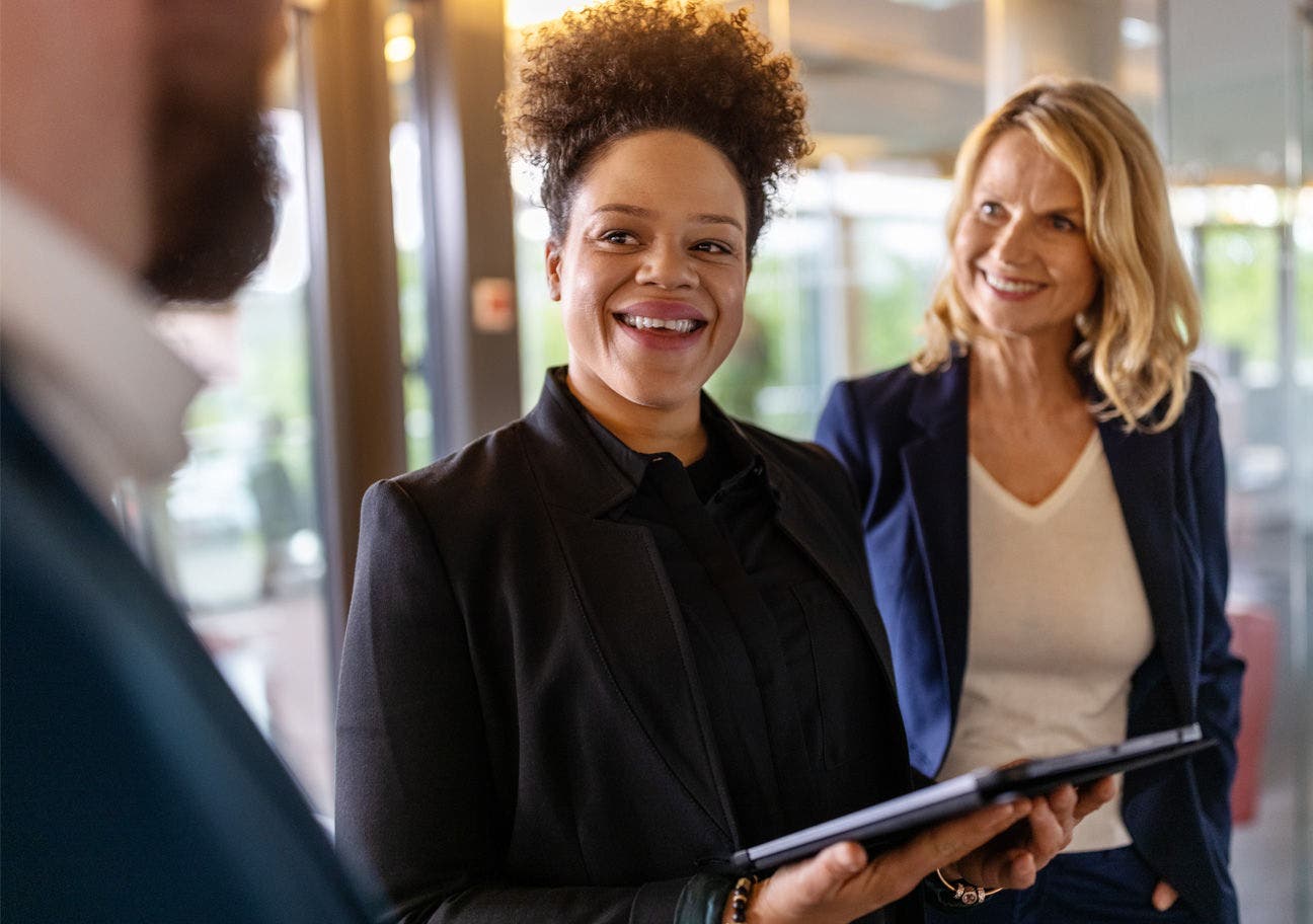 woman holding ipad smiling with two other people