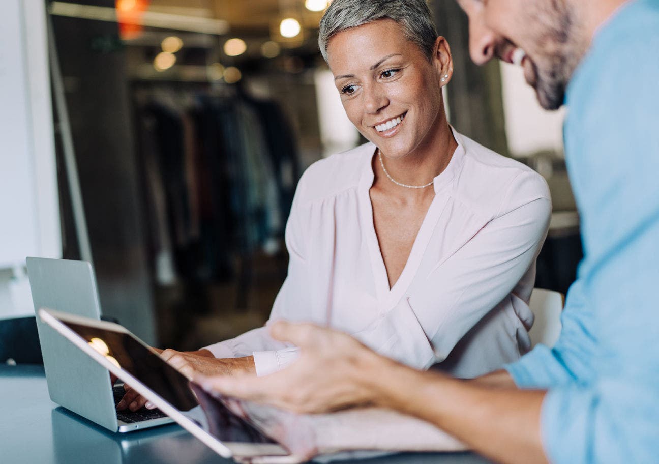 woman with a laptop talking to a man with a tablet