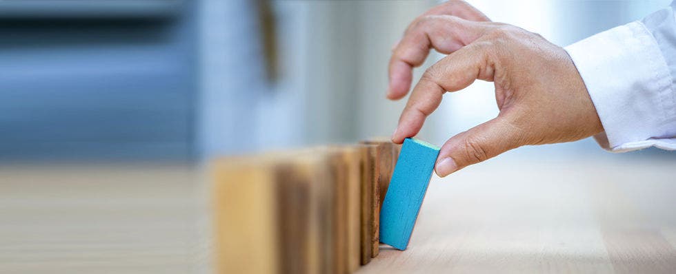 A hand setting up building blocks