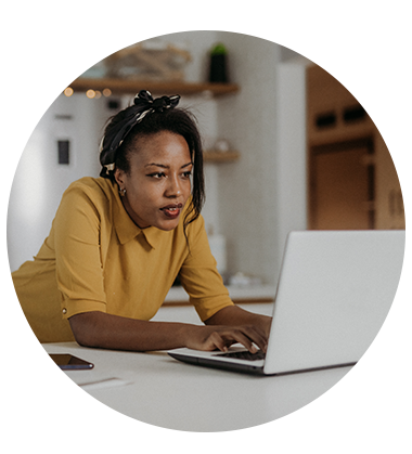 A woman standing at a countertop, typing on a laptop