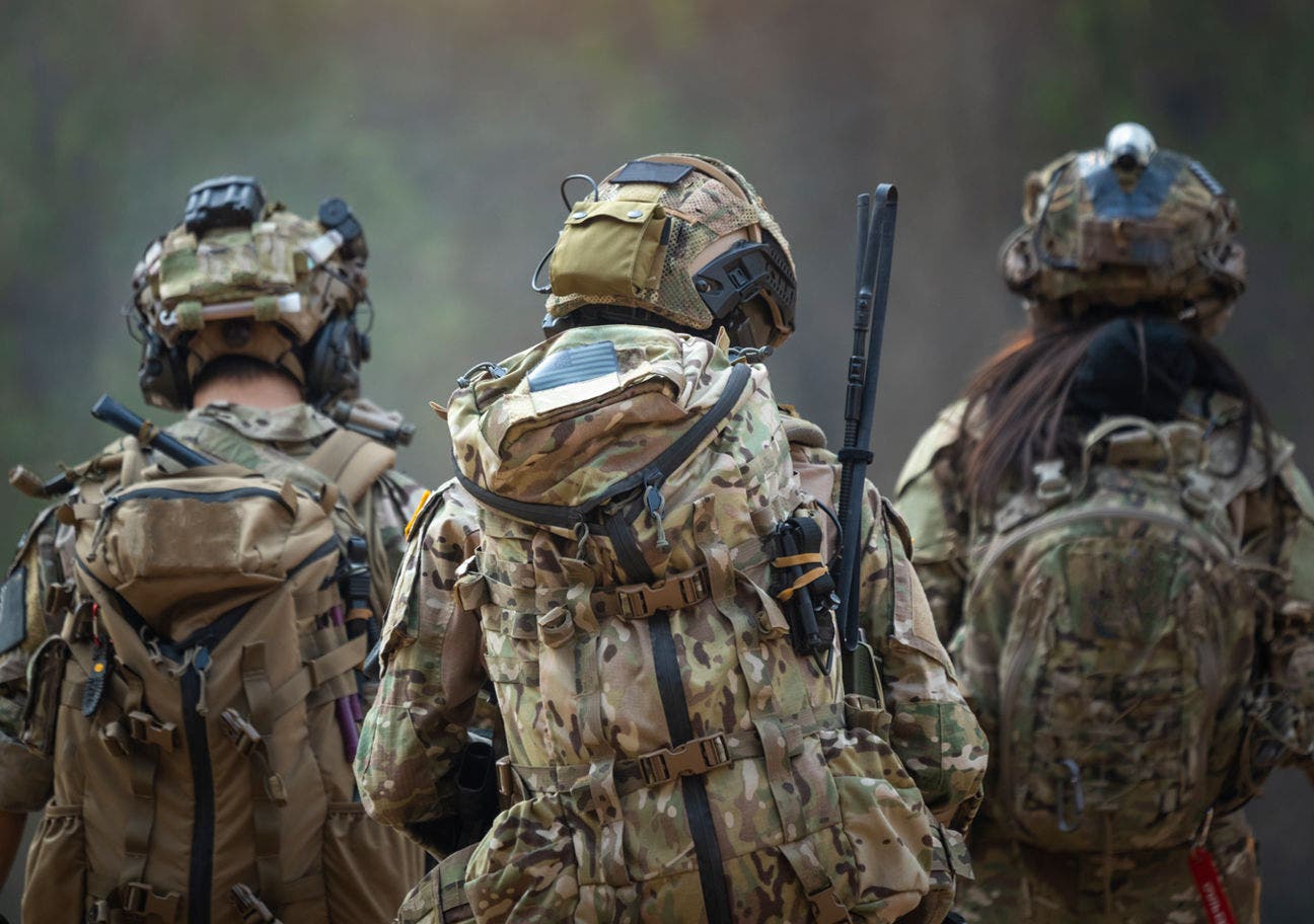 three soldiers in combat gear facing away from the viewer