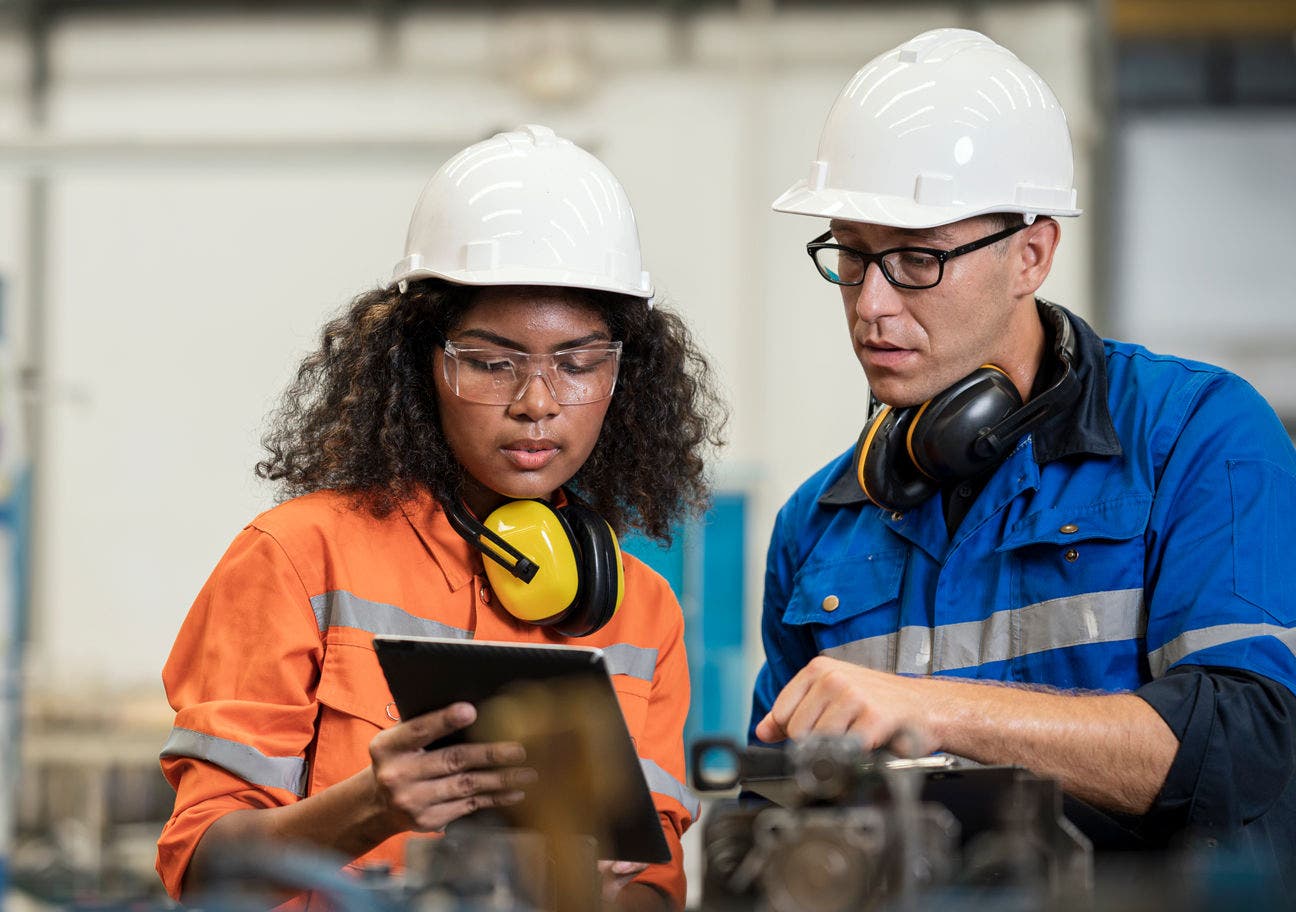 two factory workers looking at a tablet