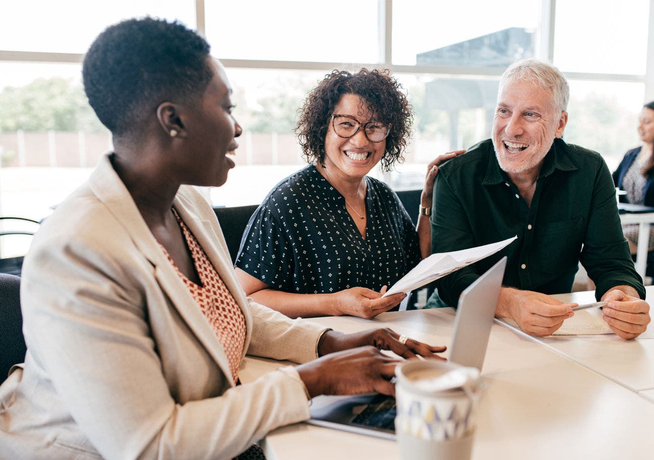three people sitting at a conference table laughing