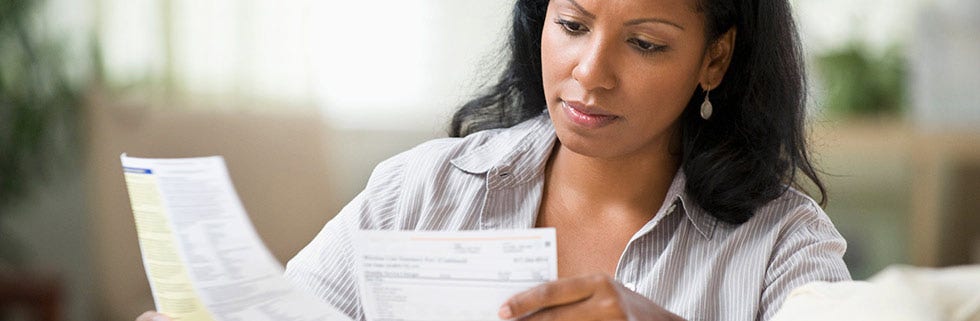 Person reviewing bills and financial documents at home, representing the challenges of managing credit and expenses during financial hardship.
