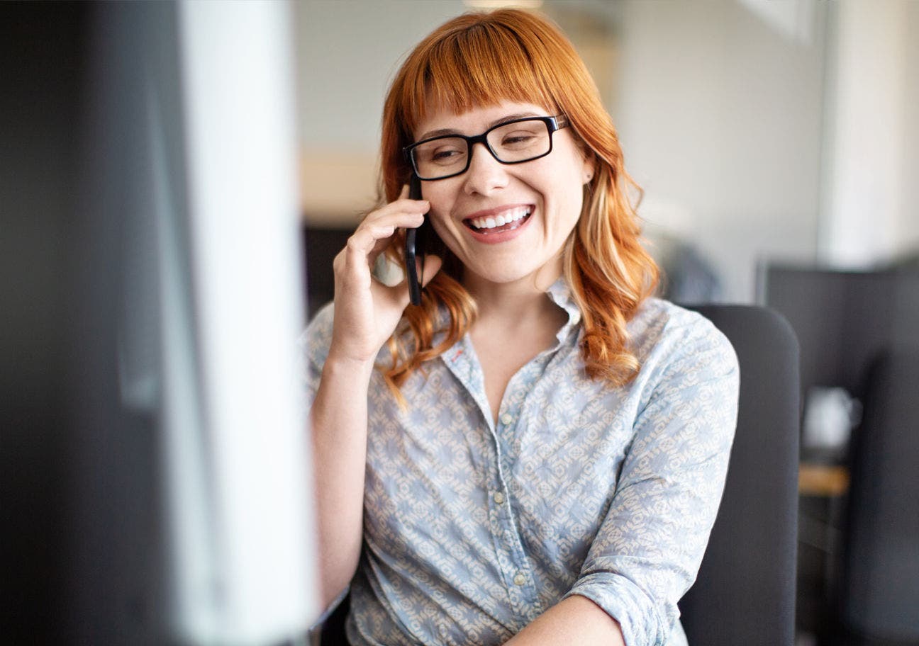 woman talking on the phone while using a computer