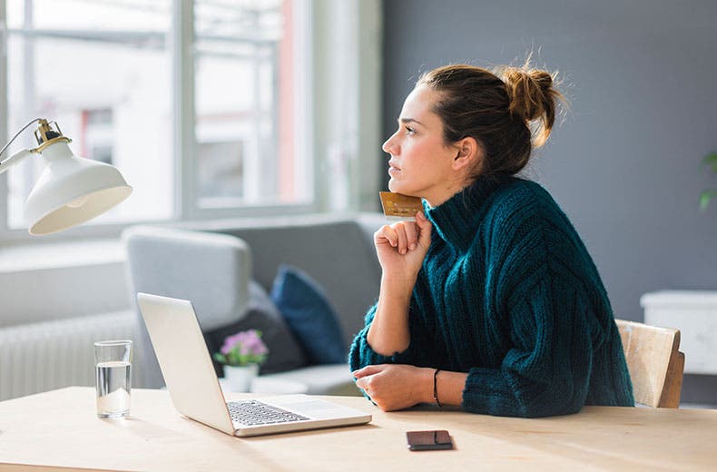 woman holding credit card by laptop