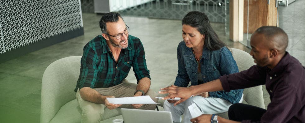 Group of people in an office environment sitting around a computer.