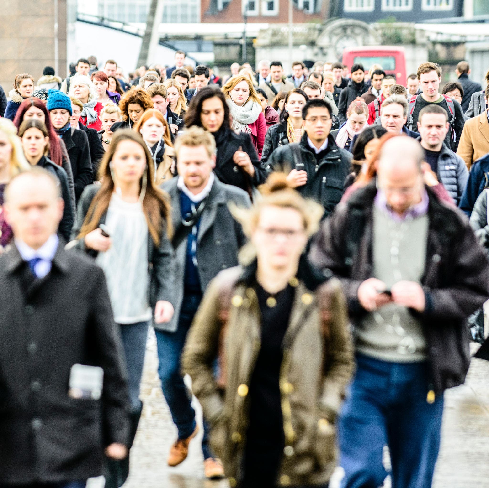 Large group of people walking the same way, lost in their own thoughts on the way to work. Modern life.