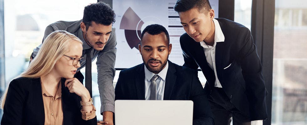 three men and one woman in suits looking at laptop