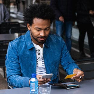 man looking at credit card and phone