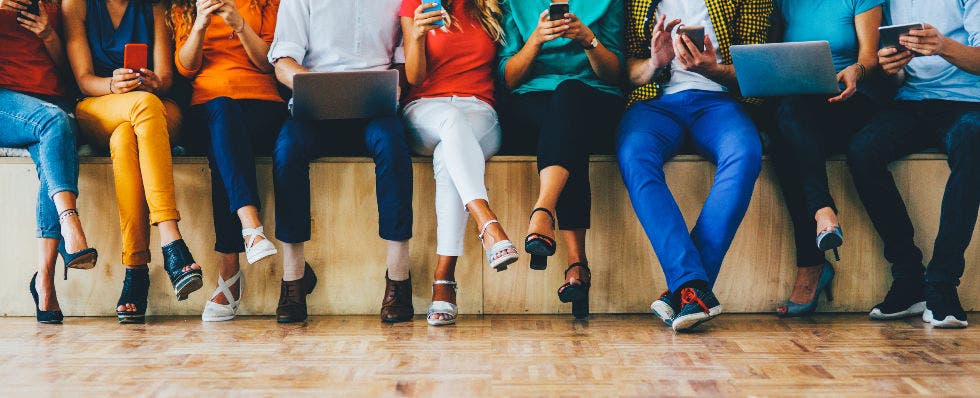 An image of a lineup of people on phones and laptops.