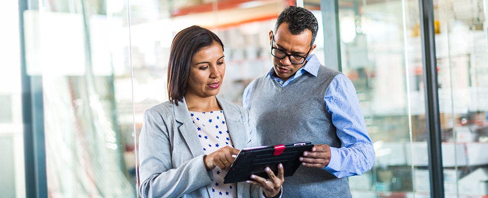 Photo of two people in an office looking at a tablet computer. 