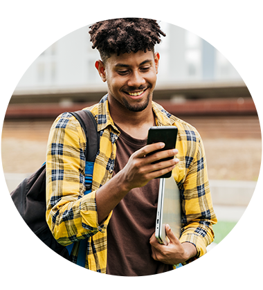 Man wearing yellow flannel shirt with backpack looking at his phone