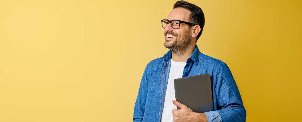 man smiling with glasses on yellow background