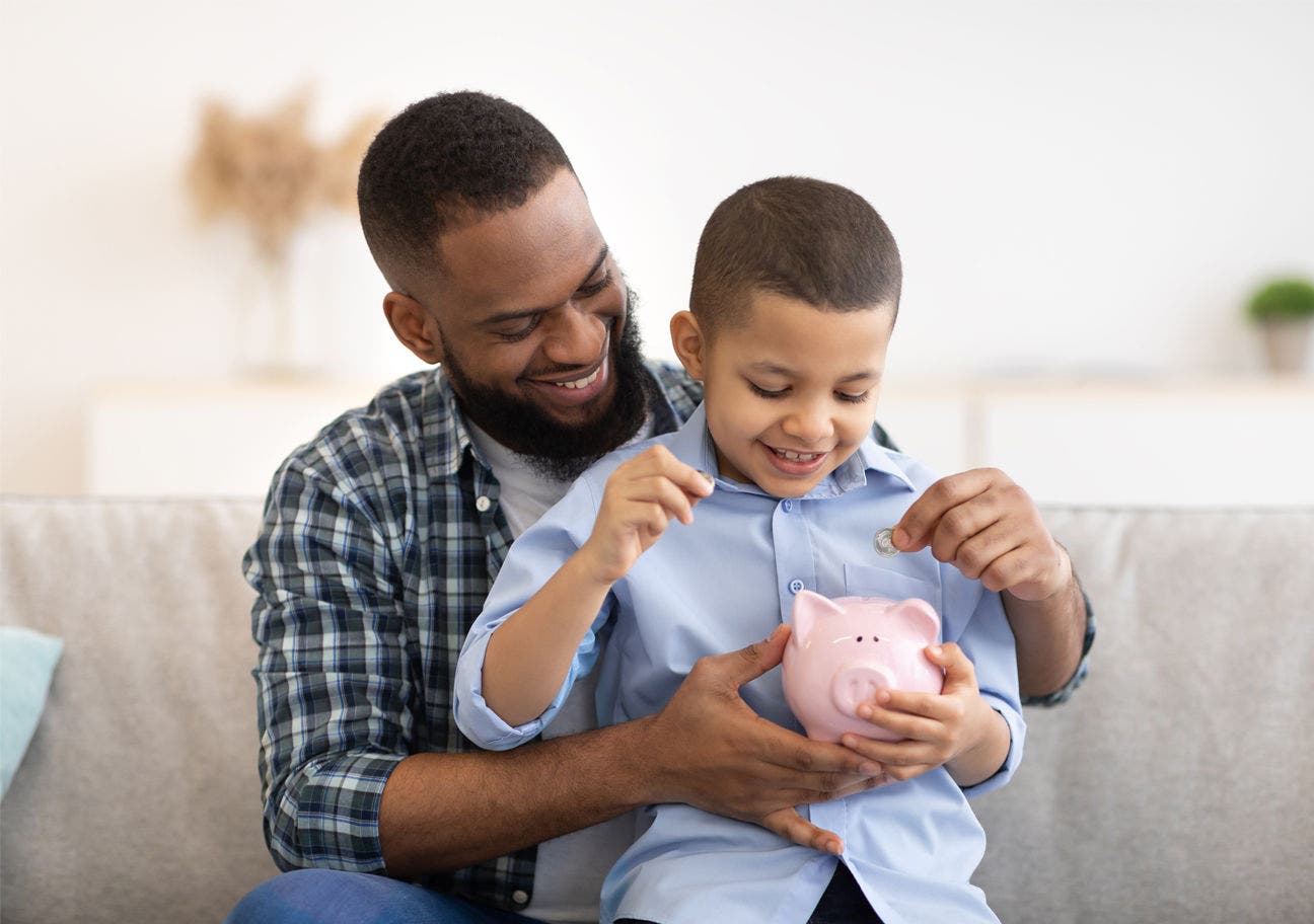 Father and son adding change to piggy bank