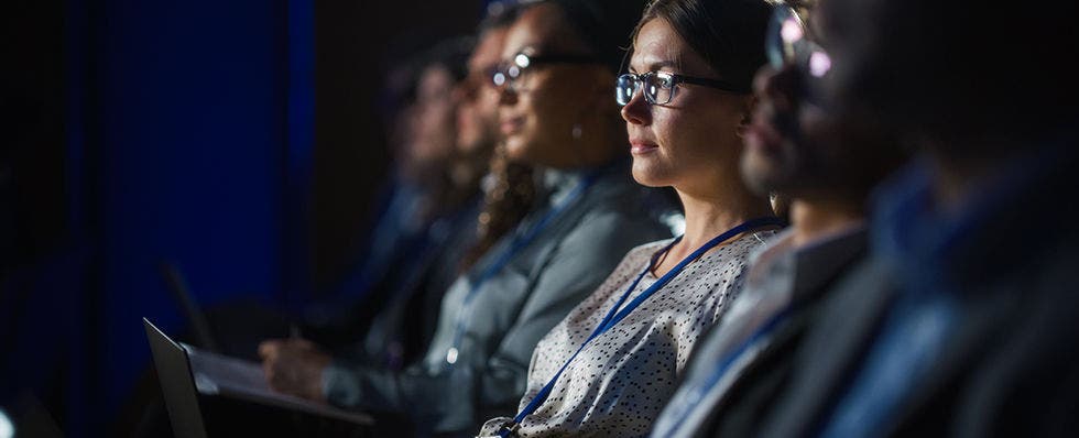 Audience at business event with focus on a woman