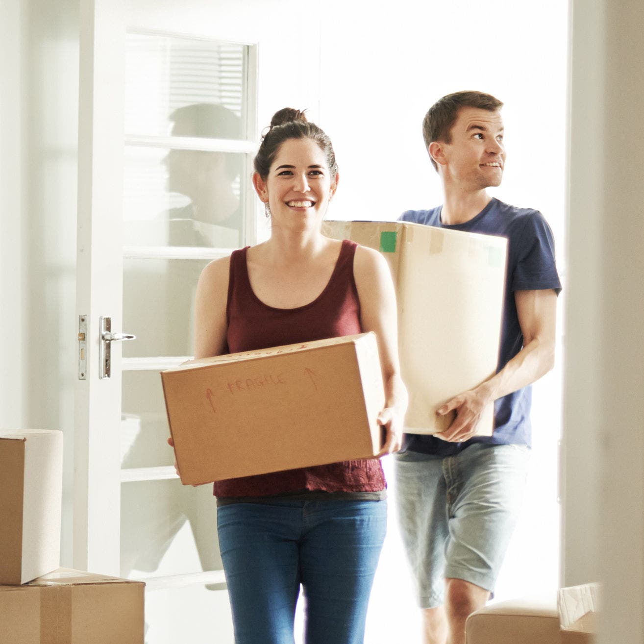 man and woman carrying moving boxes
