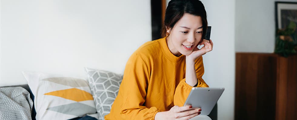 woman holding credit card looking at tablet