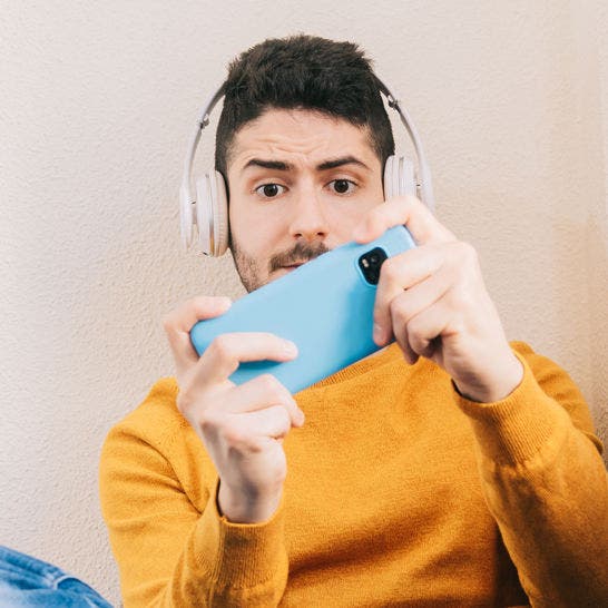 man wearing headphones playing a game on his smartphone