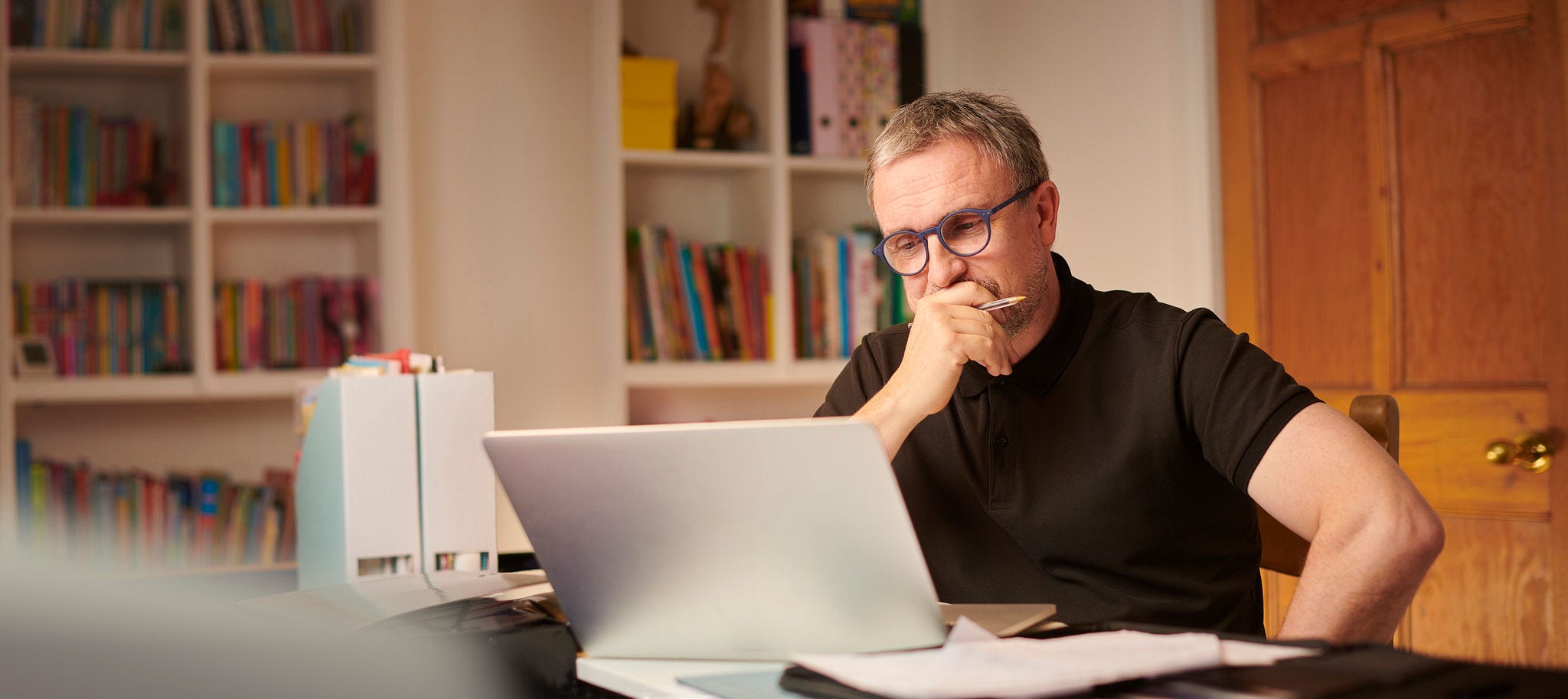 Man looking worriedly at laptop computer on desk. 