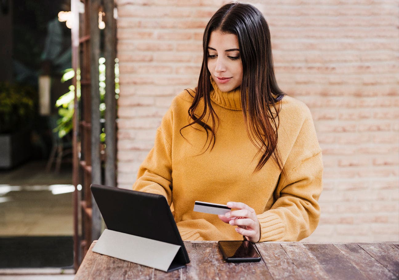 woman holding a credit card while using a tablet