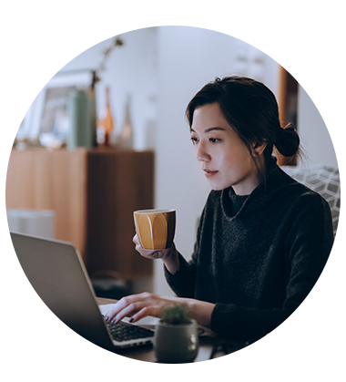 Woman typing on laptop and holding coffee in her right hand