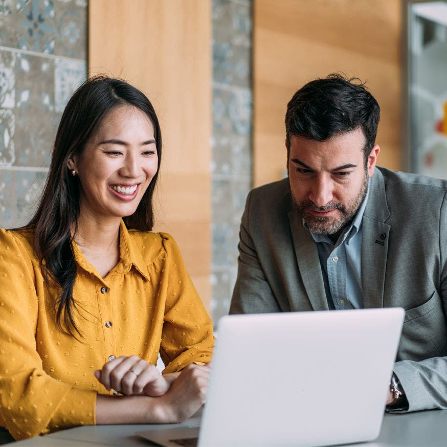 two people one female asian and one man with beard looking at laptop