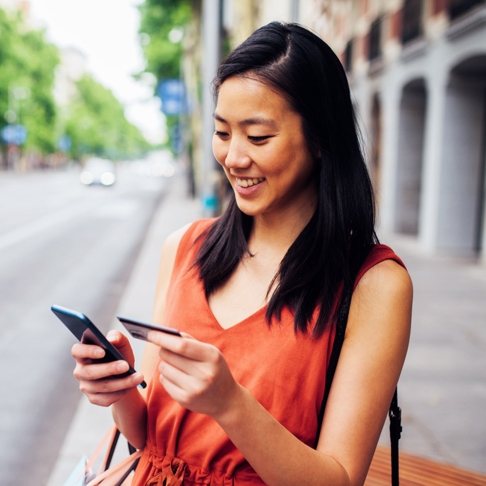 smiling woman holding credit card and mobile phone