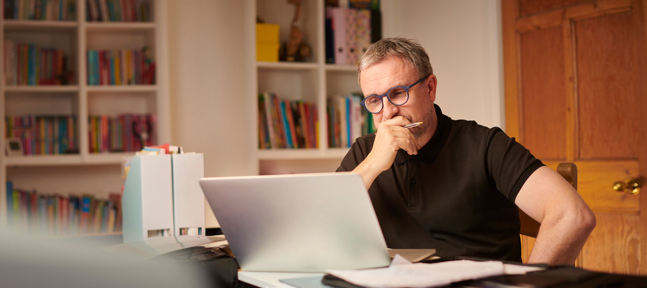 Man looking worriedly at laptop computer on desk. 