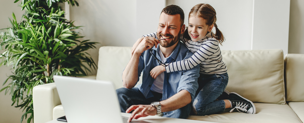 father and daughter smiling at computer