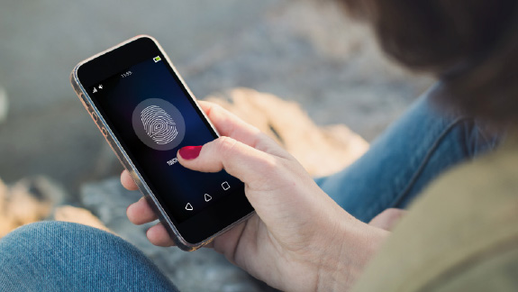 Woman scanning thumbprint on mobile phone.