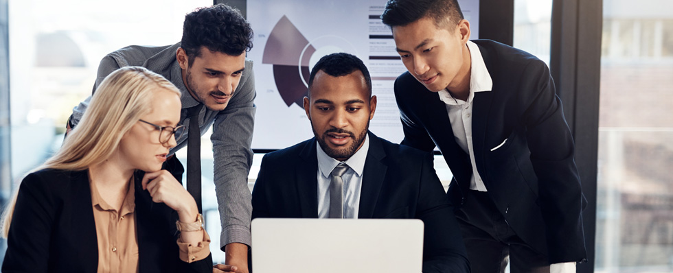 three men and one woman in suits looking at laptop