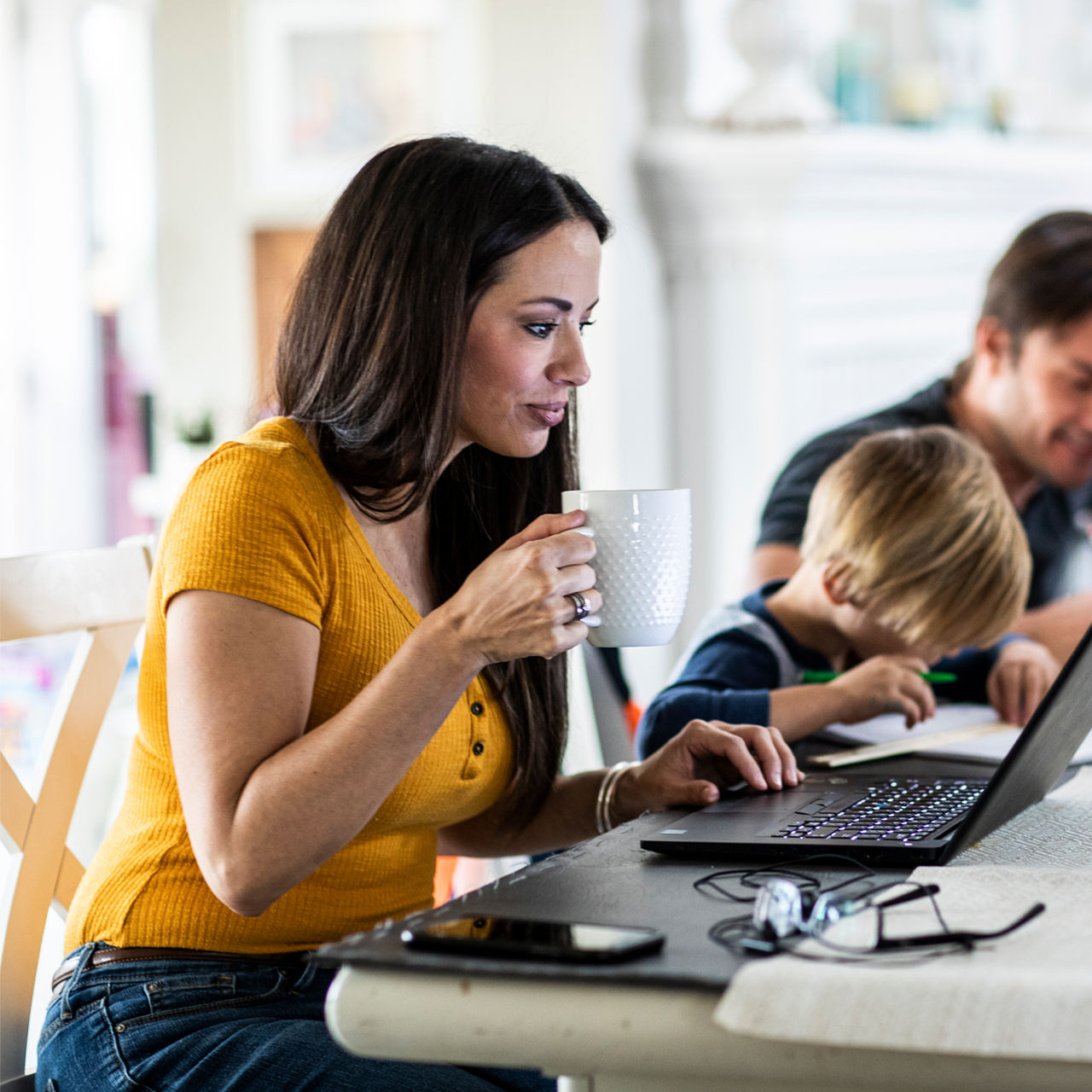 mother working on laptop with family nearby