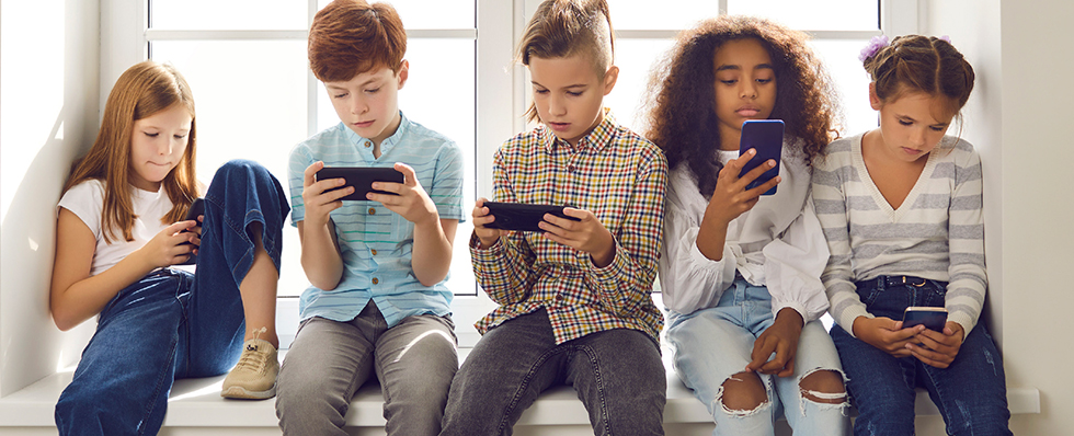 Five children using mobile phones. 